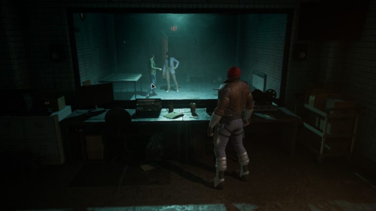 A screengrab from Gotham Knights showing the Red Hood staring through two-way glass at a police station